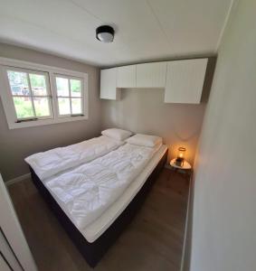 a bedroom with a bed with white sheets and a window at Park De Driesprong in Nieuwveen