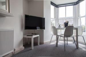 Cette chambre blanche dispose d'une table, de chaises et d'une télévision. dans l'établissement Stunning 2 bed apartment with sea views, Penzance, à Penzance