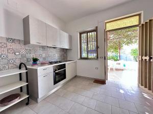 a kitchen with white cabinets and a large window at Villa Eleonora in Palmi