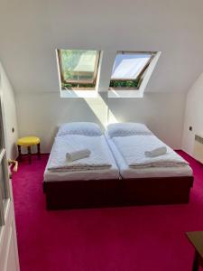 two beds in a small room with two windows at Penzion Breuer in Jablonec nad Jizerou