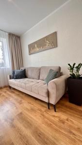 a couch in a living room with a wooden floor at LILLE`S apartment in city center in Alūksne