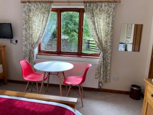 Zimmer mit einem Tisch, 2 Stühlen und einem Fenster in der Unterkunft Sunset House B&B in Penrith