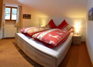 a bedroom with a bed with red and white pillows at Haus Sonnbichl in Schliersee