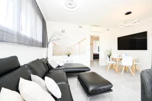 sala de estar con sofá de cuero negro y TV en Katya Resort Superior Apartments - MGH en Desenzano del Garda