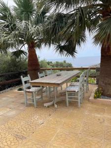a wooden table and chairs on a patio with palm trees at Souda’s nest in Plakias