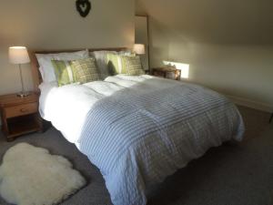 a bedroom with a large bed with a white comforter at Juniper Cottage in Clovenfords