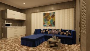 a living room with a blue couch and a kitchen at AlHamra Hotel Kuwait in Kuwait