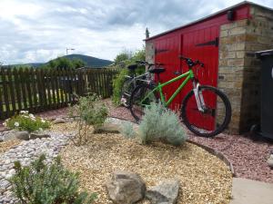 un vélo vert garé à côté d'un hangar rouge dans l'établissement Juniper Cottage, à Clovenfords