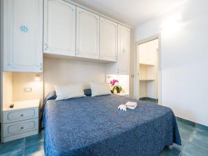 a bedroom with a blue bed and white cabinets at Green Village Resort in Villasimius