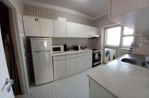 een keuken met witte kasten en een witte koelkast bij Vila Mar Apartment in Vila do Conde +13 foto's