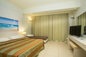 a hotel room with a bed and a flat screen tv at Lindos White Hotel & Suites in Líndos