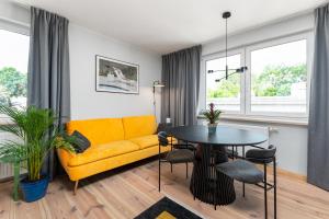 a living room with a yellow couch and a table at Walecznych 51 by Homeprime in Warsaw