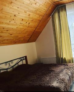 1 dormitorio con cama y techo de madera en Belvedere-Karpaty, en Skhidnytsya