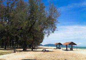 a sandy beach with trees and shelters and the ocean at Sulong Inn - Private Pool Homestay in Kuantan, Pantai Sepat in Kuantan