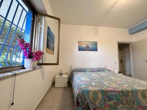 a bedroom with a bed and a window with flowers at Villa Eleonora in Palmi