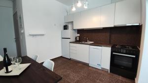 a kitchen with white cabinets and a table and a black oven at SUN KISS HOUSES Sun Kiss Houses B in Áyios Spirídhon