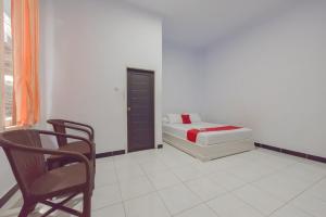 a bedroom with a bed and a chair in it at RedDoorz Syariah near Ramayana Mall Tarakan in Tarakan