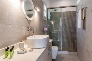 ein Badezimmer mit einem Waschbecken, einem WC und einem Spiegel in der Unterkunft Afroditi Ftelia Anemone in Ftelia