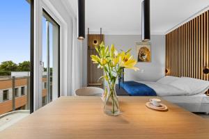 a vase of yellow flowers on a wooden table in a room at Nena Apartments Berlin - Adlershof - "New Opening 2024" in Berlin