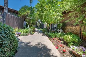 a walkway in a garden with flowers and a fence at Talia Cabin Guest & Spa in Rosh Pinna