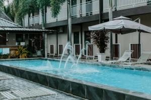 a pool with a fountain in front of a hotel at Destini Akef Villa in Pantai Cenang