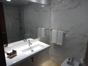 Baño blanco con lavabo y espejo en Hotel Lloret Ramblas, en Barcelona