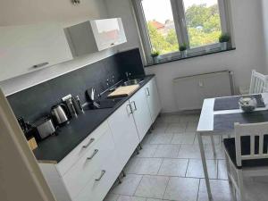 eine Küche mit weißen Schränken und einer schwarzen Arbeitsplatte in der Unterkunft Gästehaus Brunswiek Obergeschoss in Vordorf