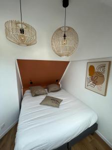 a bed in a room with two pendant lights at Maison de charme avec jacuzzi - Bretagne / île de Batz in Île de Batz