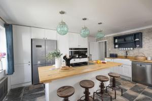 una cocina con armarios blancos y una barra con taburetes en Chyvounder, Sennen en Trevilley
