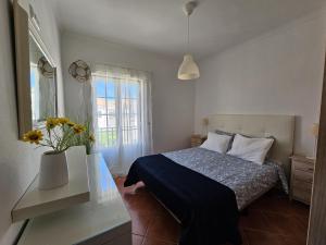 - une chambre avec un lit et un vase orné de fleurs dans l'établissement Casa de praia em Almograve, à Almograve