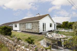 a white cottage with a table and chairs in the yard at Chyvounder, Sennen in Trevilley