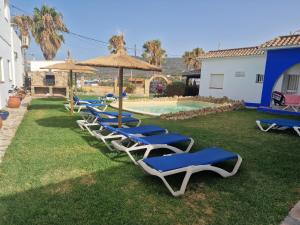 a row of lounge chairs with umbrellas and a pool at Habitaciones Miramar in Bolonia