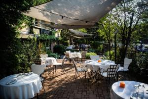 een patio met witte tafels en stoelen in een tuin bij 205m2 Penthouse with 75m2 Castle View Terrace and Barbercue - My Loft in Budapest in Boedapest