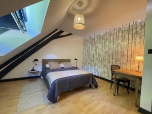 een slaapkamer op zolder met een bed en een bureau bij Gite du vieux Morat in Saint-Bonnet-Tronçais