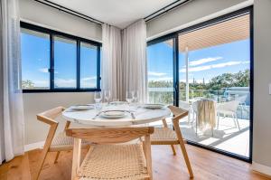 een eetkamer met een tafel en stoelen en grote ramen bij Essence Boutique Hotel in Peregian Beach