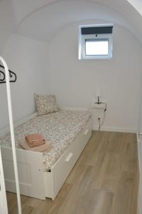a bedroom with a white bed with a wooden floor at Casa dos Albardeiros in Moura