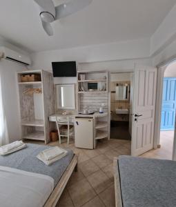 a bedroom with two beds and a desk and a kitchen at Harama hotel Schinoussa in Schinoussa