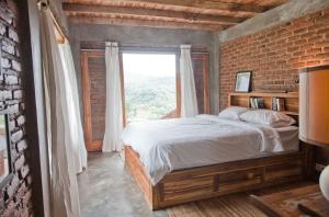 a bedroom with a bed and a brick wall at Bukit Cottage Pak Ansel in Labuan Bajo