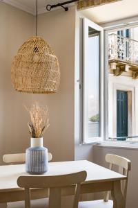 a dining room table with a rattan light fixture at Fotiadis Family Luxury Suites by Konnect in Corfu Town