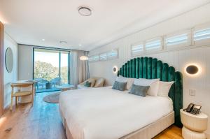 a bedroom with a large bed with a green headboard at Essence Boutique Hotel in Peregian Beach