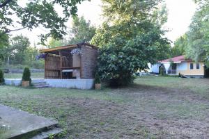 a small building in a yard with a tree at Вили Водно Конче Villas Vodno Konche in Ahtopol