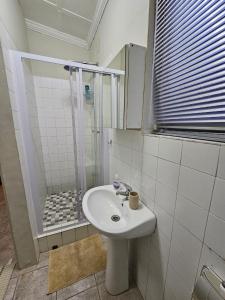 a bathroom with a white sink and a shower at Private Guest Suite with 24hr Electricity, East London in East London