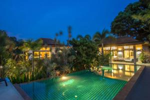 a swimming pool in front of a house at night at Luxury 6BR Pool Villa Oxavia next to NaiHarn Beach in Rawai Beach