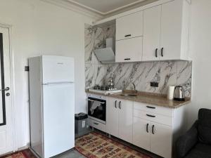a kitchen with white cabinets and a white refrigerator at Olympos Likya Apart Otel in Yenbey