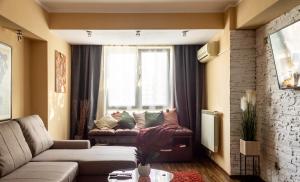 Una sala de estar con un sofá y una ventana. en Sky Paradise - M&N Condos, en Bucarest