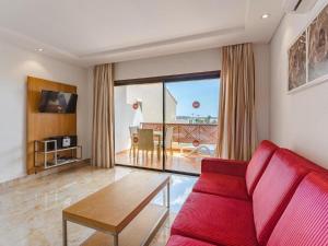 a living room with a red couch and a table at 349 Apartamento Golf del Sur Albatros in San Miguel de Abona