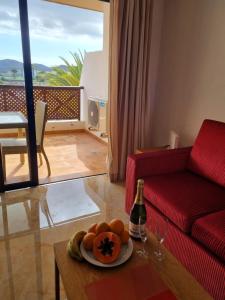 a living room with a red couch and a table with a plate of food at 349 Apartamento Golf del Sur Albatros in San Miguel de Abona