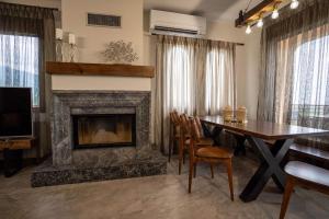 a dining room with a fireplace and a table and chairs at Olympus Mythical Resort in Skotina
