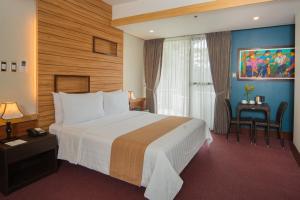 Grand Sierra Pines Baguio في باغيو: غرفة فندقية بسرير كبير ونافذة