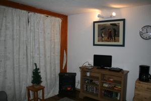 Les Allues的住宿－Ski in and Out 2-Bed Apartment in Meribel，客厅配有电视和带时钟的桌子
